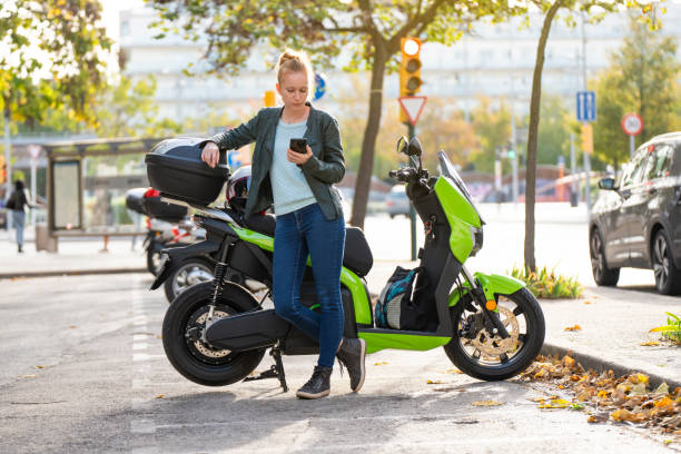 istock Red-haired woman using the smart phone next to her parked motorcycle 2141268525