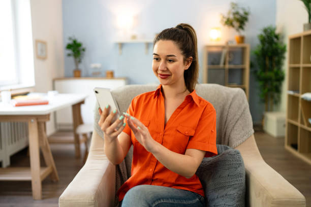 istock Young Caucasian woman using phone while relaxing at home 2141279234