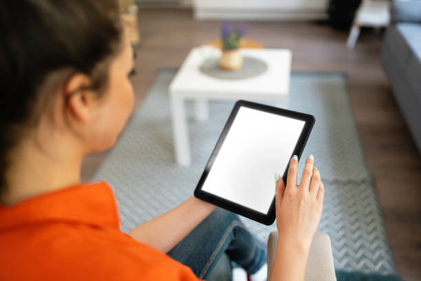 istock Young woman using digital tablet while relaxing at home 2141279438