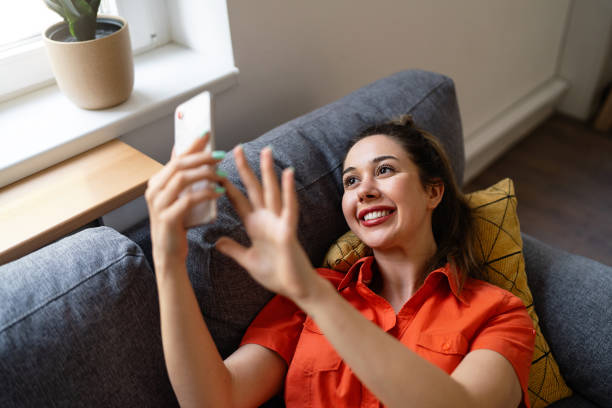 istock Young Caucasian woman using phone while relaxing at home 2141280292