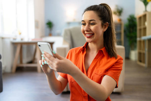 istock Young Caucasian woman using phone while relaxing at home 2141281900