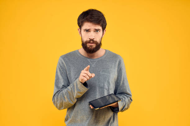 istock Emotional man with tablet in hands technology internet device lifestyle yellow background 2141287203