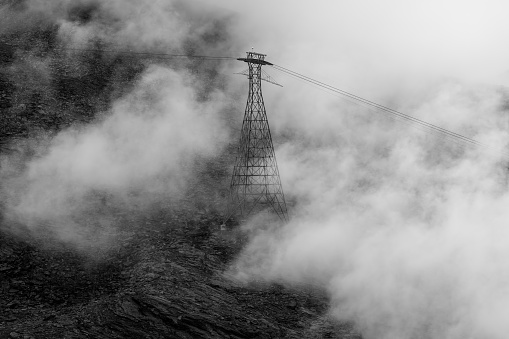 A transmission tower rises above a thick layer of low clouds at the summit