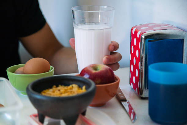 Mano de deportista sosteniendo un vaso de leche fresca. - foto de stock