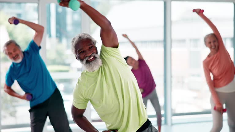 Fitness, weights and elderly people in gym for health, wellness and arm workout class. Sports, diversity and senior friends stretching for muscle exercise or training with dumbbells in studio.