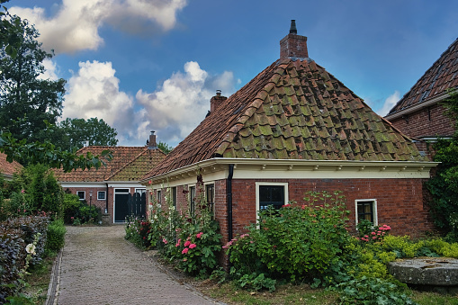 Tinallinge, Netherlands, July 15, 2023. Characteristic streetscape in a traditional northern-Dutch village, with historic houses and small gardens with colorful flowers. Tinallinge, province of Groningen