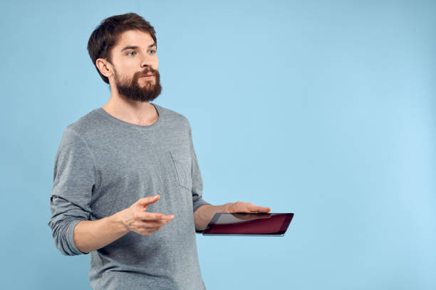 istock Man holding tablet in hands wireless technology internet lifestyle studio blue background emotions 2141389449