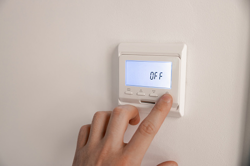 White thermostat for heating the warm electric floor and the boiler on the wall. the person turned off the finger control. information on the electronic display with backlight Off. ost saving
