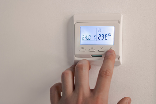 White thermostat for heating the warm electric floor and the boiler on the wall. the person turned off the finger control. information on the electronic display with backlight Off. ost saving