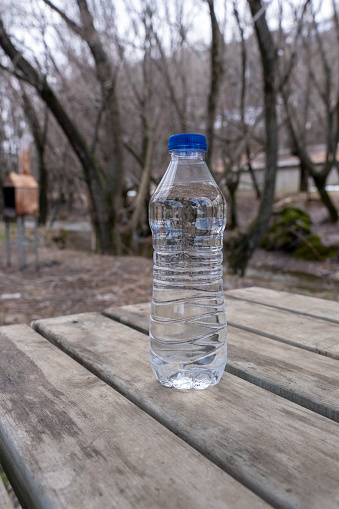 Mineral water bottle against light and trees.