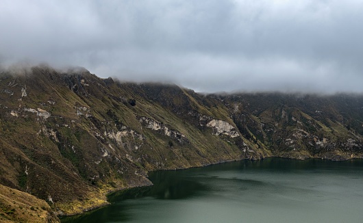 Quilotoa, Ecuador, October 20, 2022: Panoramic view of the water-filled crater lake and the most western volcano in the Ecuadorian Andes under thick clouds.