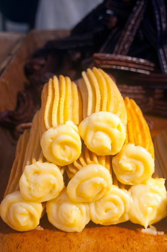 Heap of spanish churros stuffed with custard cream , spanish traditional sweet food. Close-up vertical view. Chocolate wrapped churros in the background. Copy space available.