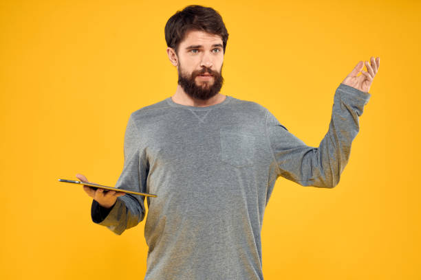 istock Emotional man with tablet in hands technology internet device lifestyle yellow background 2141478870