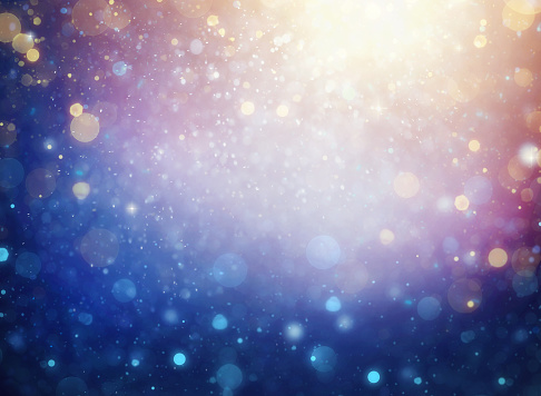 abstract background with gold and blue defocused particles and burst of light