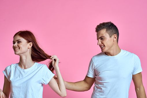 enamored man and woman hugging each other on a pink background cropped with Copy Space family portrait. High quality photo