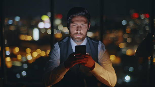 istock Corporate boss messaging mobile phone at evening city view. Late man work office 2141503830
