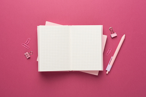 Open notebook with stationery on color background, top view