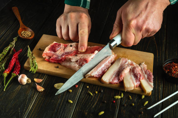 istock The chef hands use a knife to cut lard or pork belly on a kitchen board before preparing it for dinner. The concept of preparing a hearty and fatty dish 2141539976