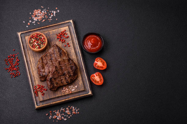 istock Fresh juicy delicious beef steak on a dark background 2141556373