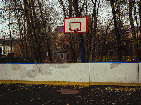 basketball court and backboard with the hoop metal ring in the city park with trees in a background..