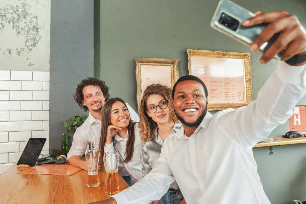 istock Multiracial group of friends taking selfies while sitting at a bar 2141587858