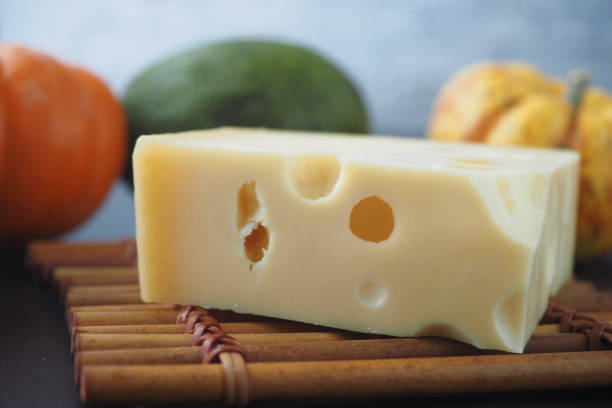 sliced cheese with holes on a chopping board on table .