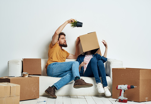 man and woman on couch moving boxes with things interior. High quality photo