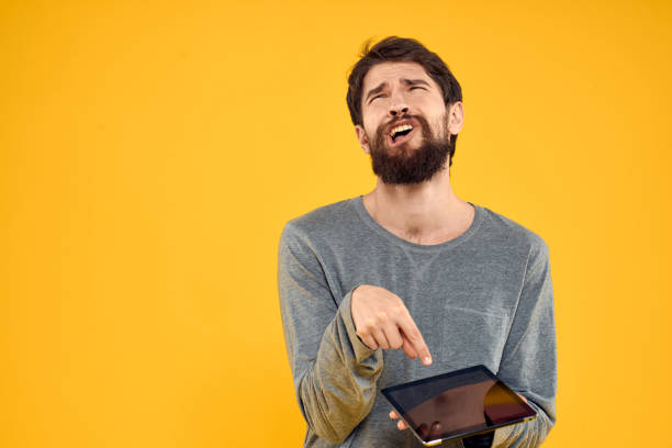 istock Emotional man with tablet in hands technology internet device lifestyle yellow background 2141648717
