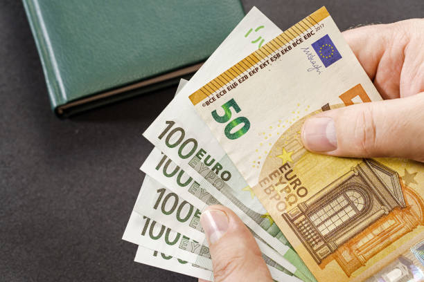 istock Holding euro cash over table 2141678353