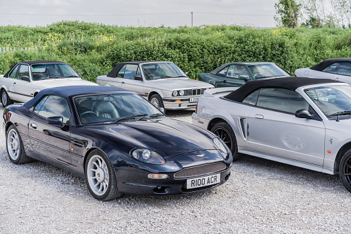 Holywell, Flintshire, Wales, May 13th 2023. Blue Aston Martin DB7 Volante and silver Ford Mustang GT Convertible at a classic car auction.