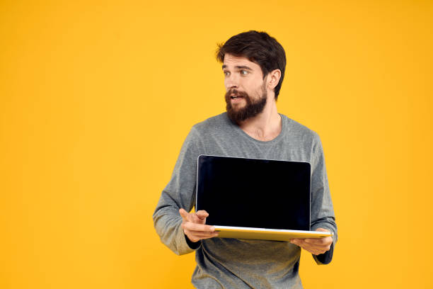 istock man with laptop wireless technology internet lifestyle work yellow isolated background 2141684196