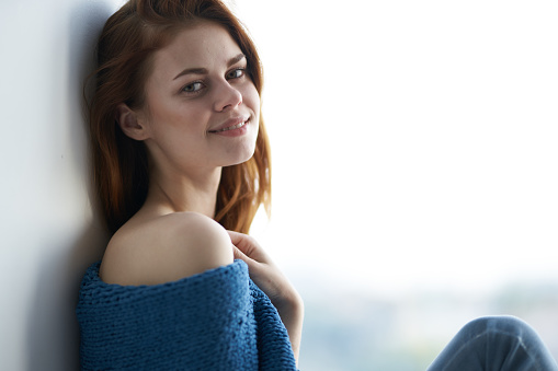 woman sits on the windowsill covered with a blanket attractive look rest. High quality photo