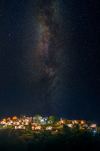 Tent Camping Village on mountain peak at night in starry sky with milky way background