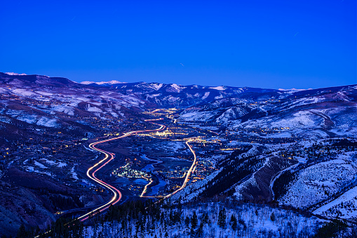 Vail Valley Winter Scenic Time Exposure - Scenic views looking at Vail Mountain in late winter/early spring with Avon and Edwards visible in foreground along Interstate 70 and the Eagle River. Time exposure at dusk/night. Mountains and valley with small towns and vehicle light trails. Vail, Colorado USA.