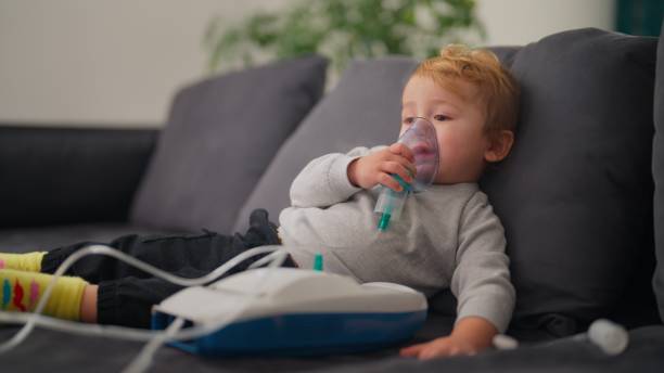 istock Preschool age boy using nebulizer while sitting on sofa in living room at home 2141721167