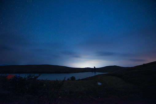 The night on the mountaintop, starry sky and lake water.