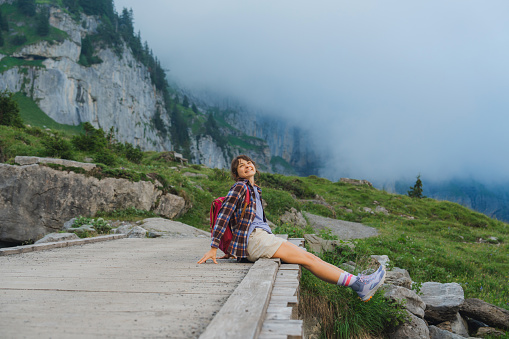Serene woman sitting on the footbridge during the hike in Swiss Alps