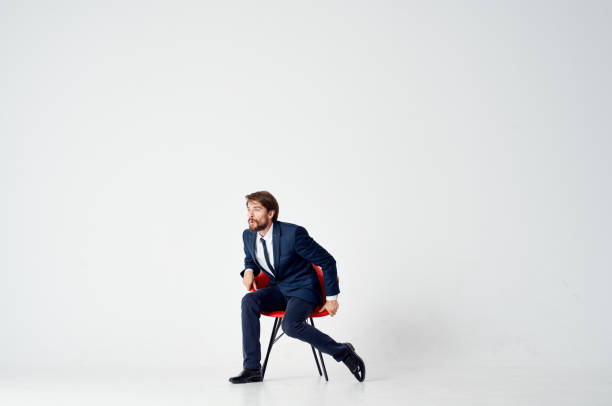 business man sits on red chairs indoors and gestures with his hands on a light background. High quality photo