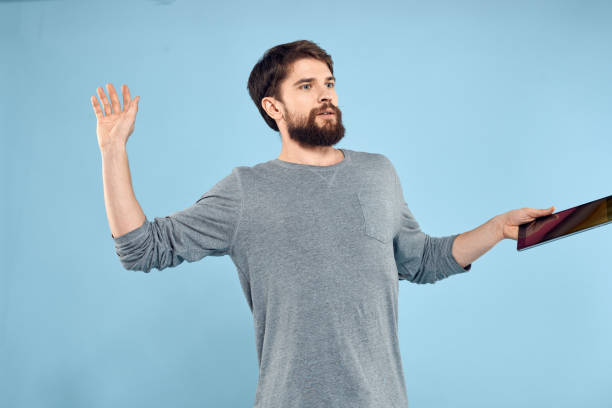 istock Man holding tablet in hands wireless technology internet lifestyle studio blue background emotions 2141770611