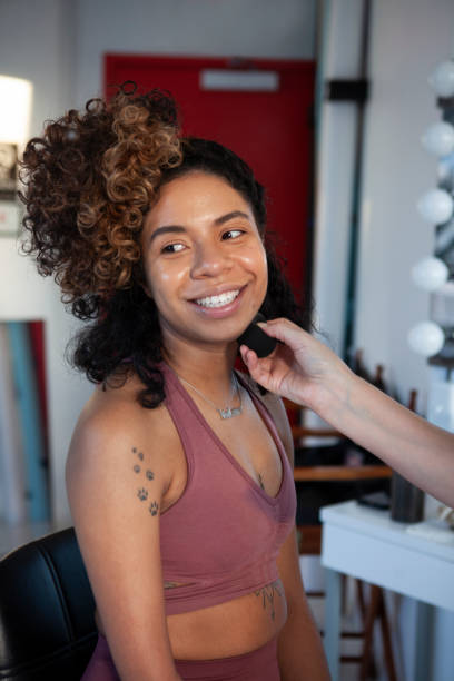 istock A woman with a limb difference is having her hair and make up done in preparation for a professional modeling session in a studio. She is looking over her shoulder and smiling. 2141806427