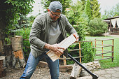 Mature adult man chopping wood in the yard