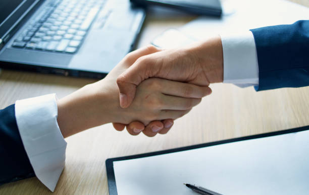 istock employees shaking hands at work in the office agreement document laptop 2141814466