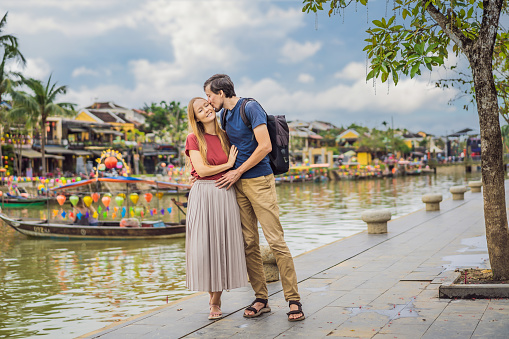 Happy couple of travelers on background of Hoi An ancient town, Vietnam. Vietnam opens to tourists again after quarantine Coronovirus COVID 19.
