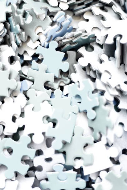Scattered white puzzle pieces on a white background. Some pieces are connected, while others are separate, creating an unfinished arrangement. The pieces have irregular shapes and smooth edges.