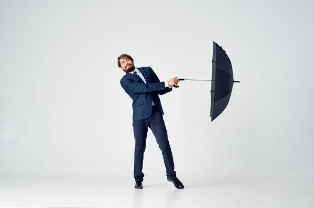 Smiling young woman while holding onto an umbrella and floating in mid air against a green wall