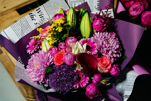 An exquisite bouquet of mixed flowers including roses and gerberas wrapped in a creative newspaper wrapping, ideal for gifting.