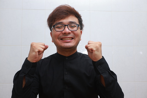 Asian man in black shirt and eyeglasses happy with his life.