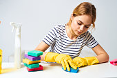 Cheerful cleaning lady wipes the table with detergents cleaning tools