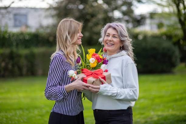 istock Mother and daughter smiling with gift and tulips. 2142110619