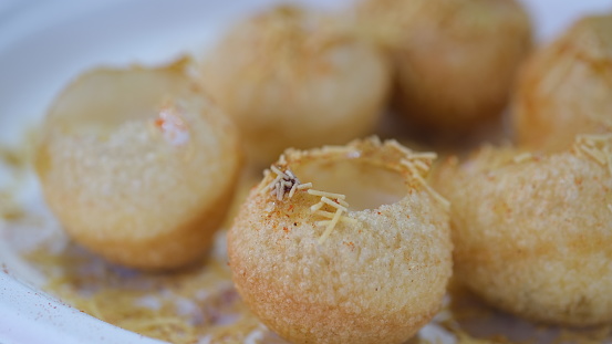 The dish is a type of chaat and originates from the city of Mumbai. It is served with mini-puri shells (golgappa)
